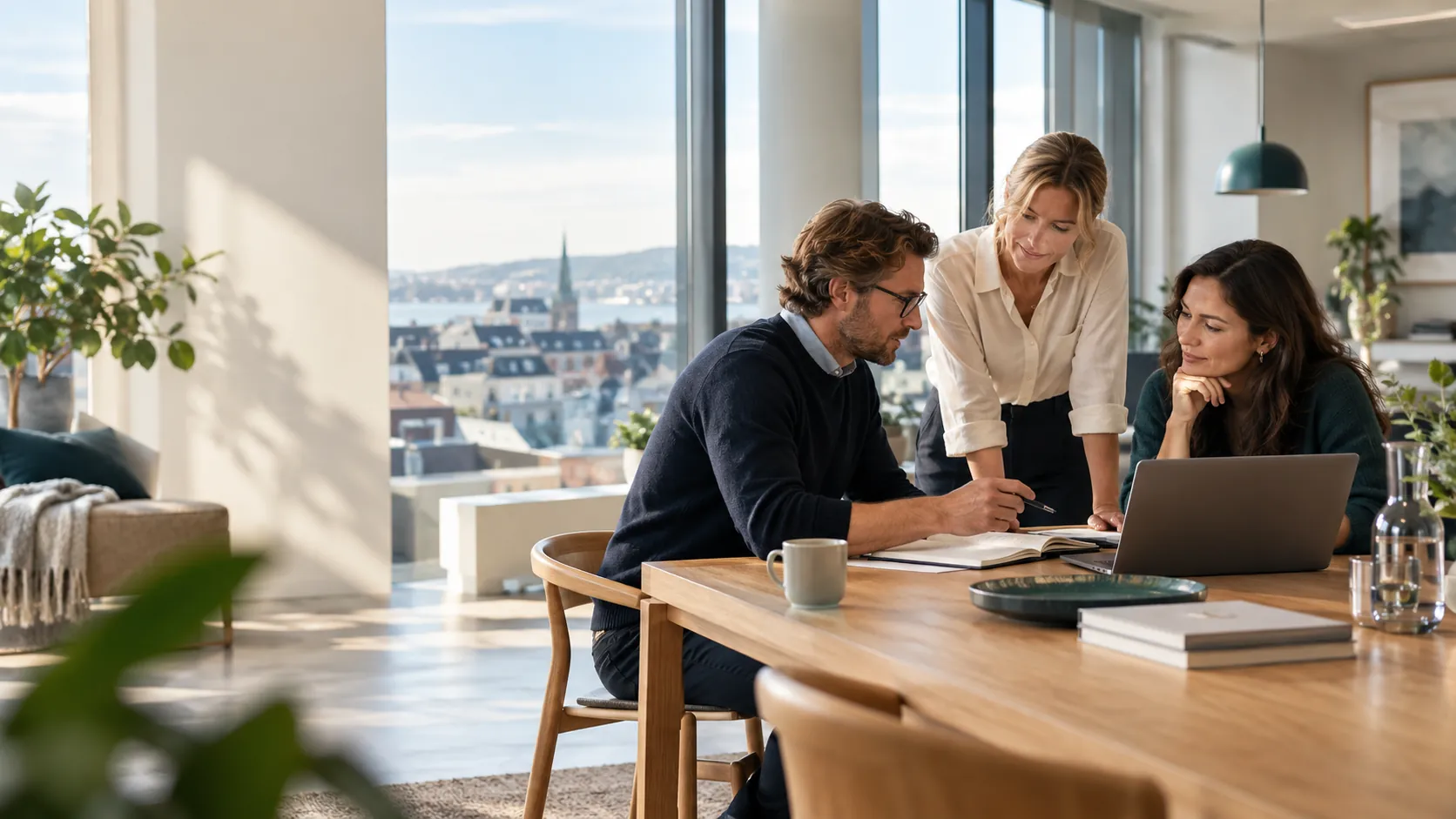 Tre kolleger diskuterer arbeidet i et lyst kontor.